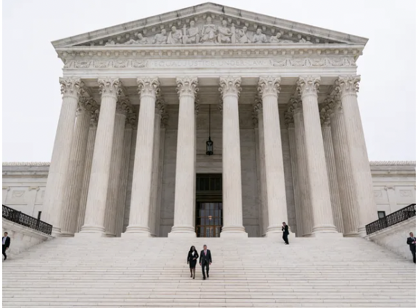 front of the supreme court building with people walking on its steps