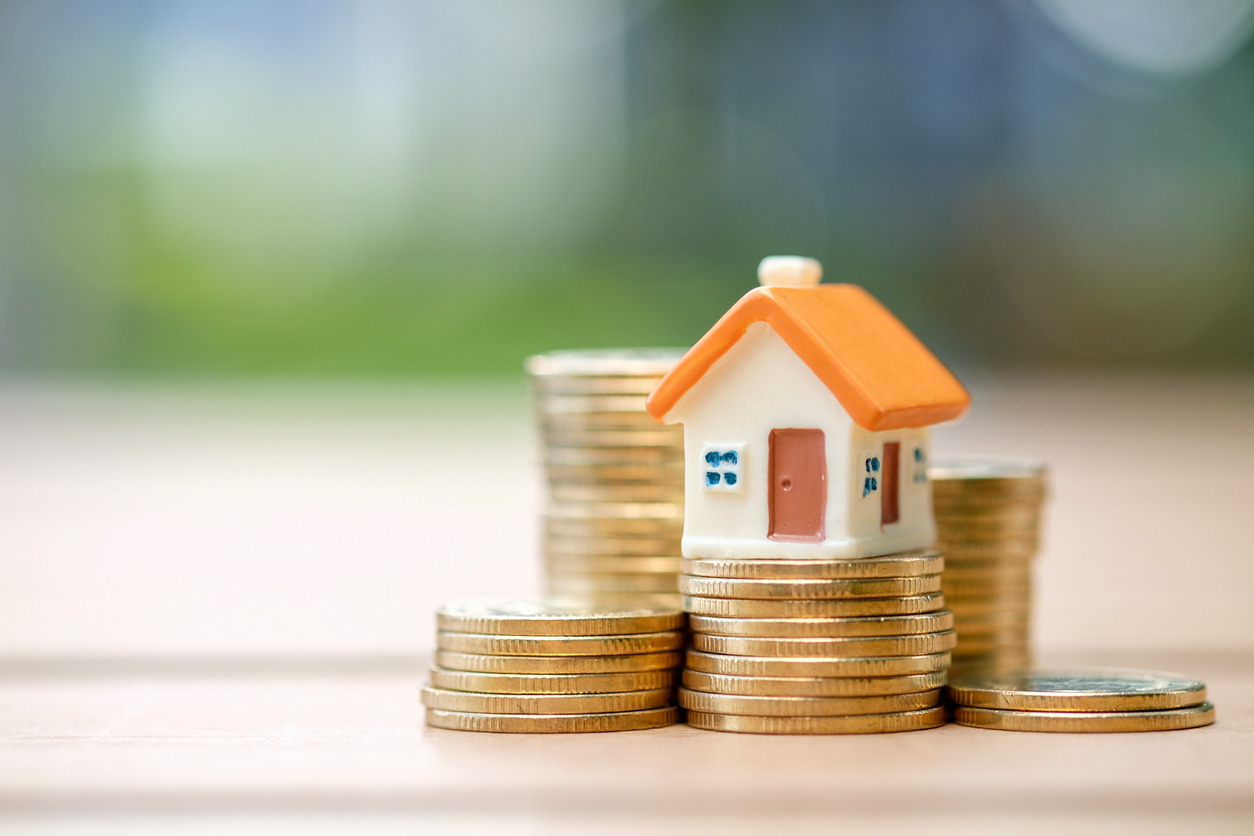 a small house standing atop of a stack of coins