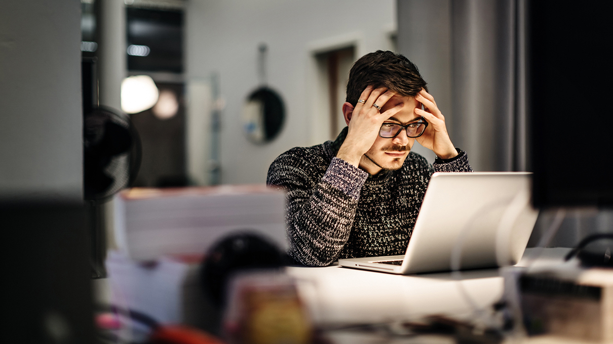 a person at a desk stressed looking at their computer